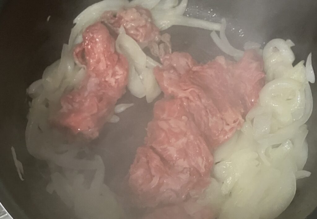 鍋に牛肉を加えて炒めている画像