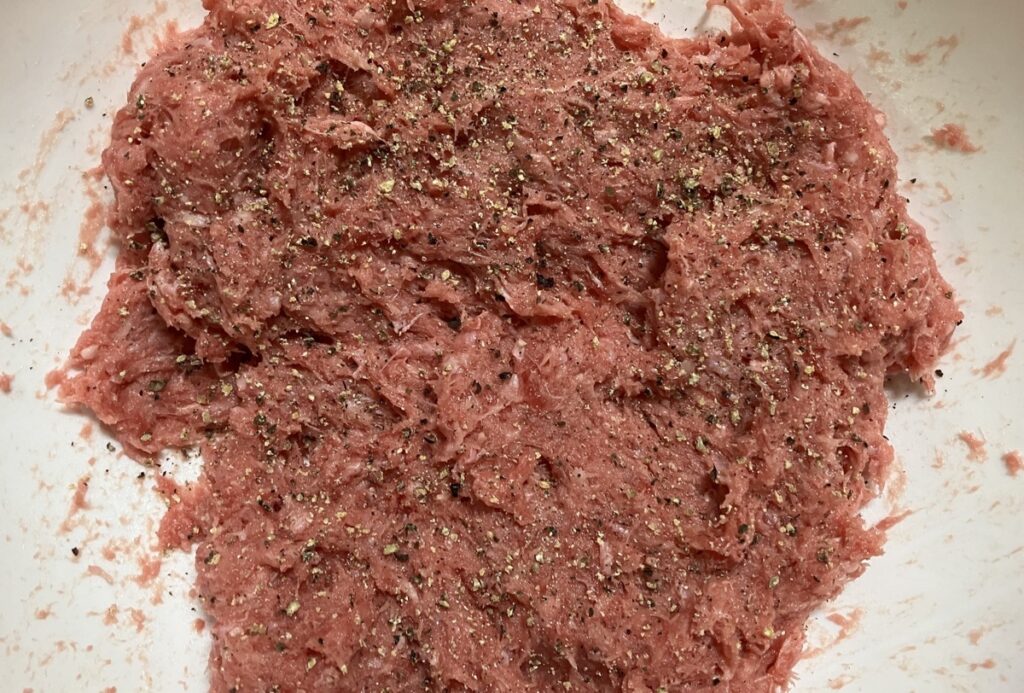 合い挽き肉と塩をボールに入れ、肉が白っぽくなるまでこね、黒胡椒を加えた画像